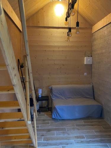 a bed in a wooden room with a staircase at Le Cartot in Saint-Sauveur-dʼÉmalleville