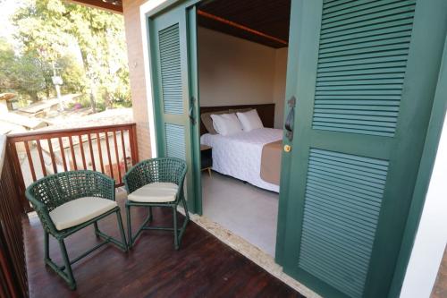 a room with a bed and two chairs on a balcony at Hotel Chale Lagoa Dos Ingas in Martins