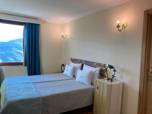 a bedroom with a bed with blue sheets and a window at Riba Loivos Village - Casa C - T3 in Casal de Loivos