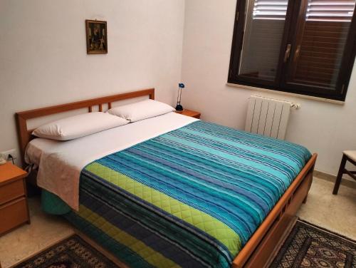 1 dormitorio con 1 cama con una manta a rayas de colores en Casa A&G, en Marsala