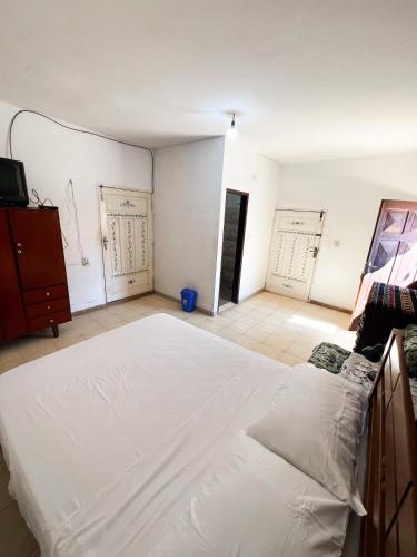 a bedroom with a large white bed and two doors at Estudio Privado en Samaipata in Samaipata