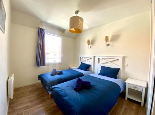 - 2 lits dans une chambre avec des draps bleus dans l'établissement La villa Astrid - 2 chambres - piscine - mer - parking, au Crotoy