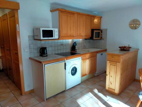 une cuisine avec un lave-linge et un micro-ondes dans l'établissement SAMOENS appartement proche du centre, à Samoëns