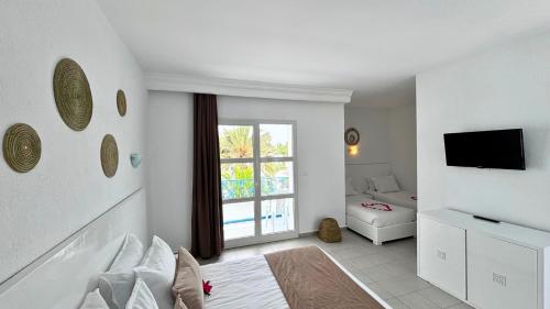 a white room with a bed and a window at Golden Tulip Président Hammamet in Hammamet