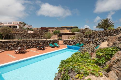 a resort pool with chairs and a rock wall at Casa Amanecer in Haría