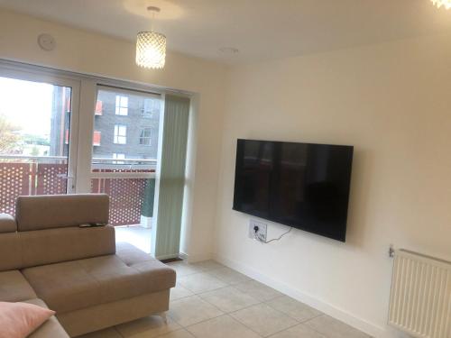 a living room with a couch and a flat screen tv at Sorbus - Flat in West Thurrock