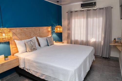a bedroom with a large white bed with blue walls at WE Hotel, La Lima in La Lima