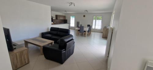 a living room with a black chair and a table at Maison du Chai in Sainte-Marie-de-Ré
