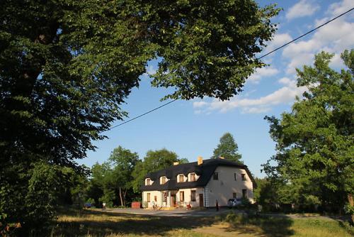 a large white barn in a field with trees at Zajazd Stok in Górecko Stare