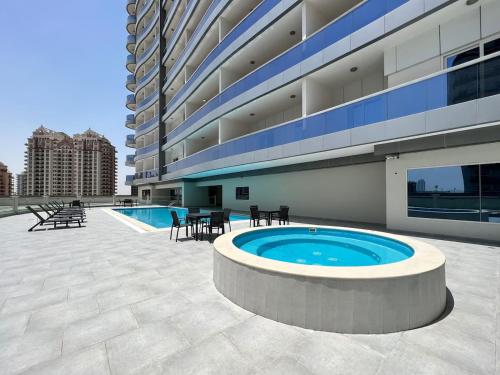 a large building with a pool and tables and chairs at Stylish Studio Urban Retreat in Dubai