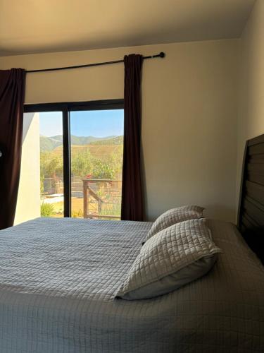 a bedroom with a bed with a large window at Coquenas del Valle in Valle de Guadalupe