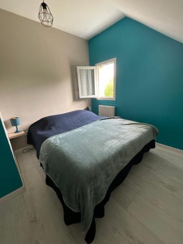 a bedroom with a large bed in a blue wall at La petite vallée in Crozant