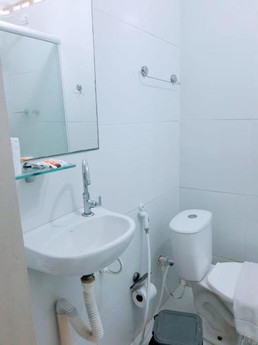 a white bathroom with a sink and a toilet at Pousada Tambaú in João Pessoa