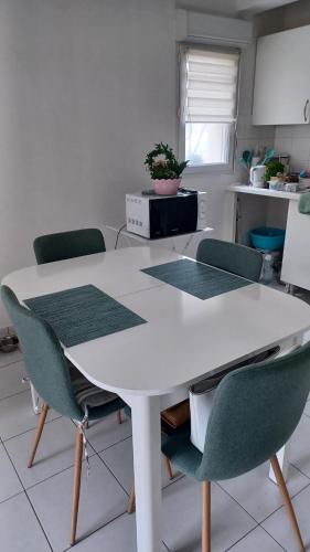 - une table blanche avec des chaises vertes dans la cuisine dans l'établissement Les régates150m de la plage 2à4 personnes Cayeux sur mer, à Cayeux-sur-Mer
