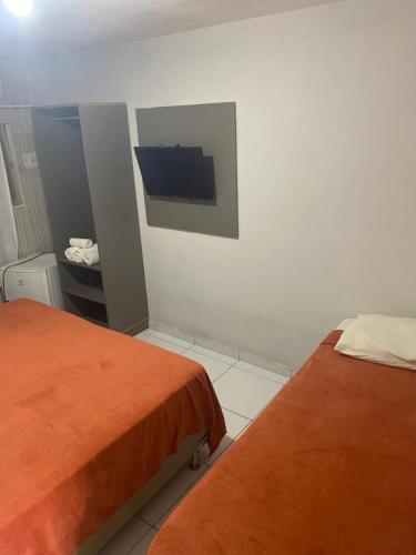 a bedroom with two beds and a tv on the wall at Pousada Tambaú in João Pessoa