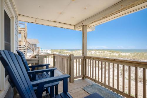 a balcony with two blue chairs and the ocean at Lowe Tide by Oak Island Accommodations in Oak Island