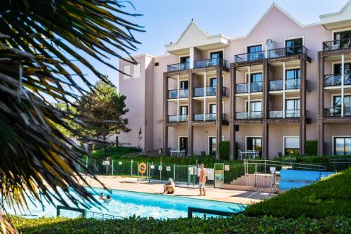 un immeuble avec une piscine devant un immeuble dans l'établissement Résidence L'Archipel - maeva Home - Appartement vue mer 3 pièces 6 personnes - Prestige MAE-6251, à Perros-Guirec