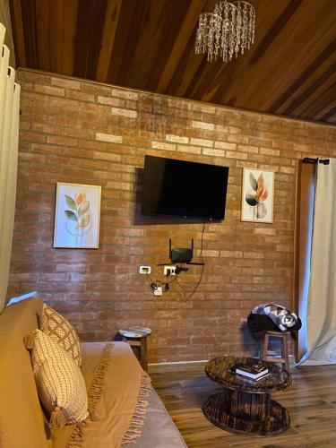 a living room with a tv on a brick wall at Chalé Magia do Serrano in São Bento do Sapucaí