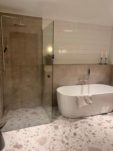 a bathroom with a tub and a glass shower at The Wooden House, Spacious, garden, new and modern in Oslo