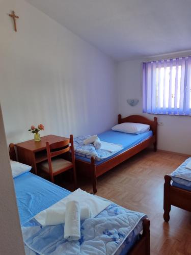 a room with two beds and a table and a desk at Rooms Zdravko and Nevenka Cilic in Međugorje