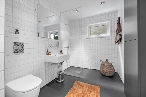 a white bathroom with a toilet and a sink at Funkisvilla med panoramautsikt in Tromsø