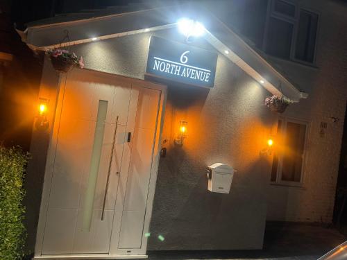 a sign on the side of a building with a door at North Avenue Guest House Ltd, Heathrow Airport-Free Parking in Hayes
