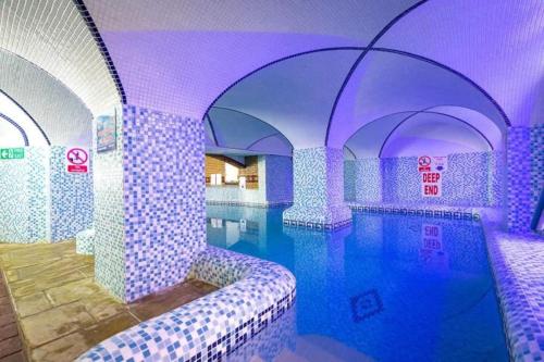 a swimming pool in a room with purple lighting at No 27 Coghurst Hall Hastings in Fairlight