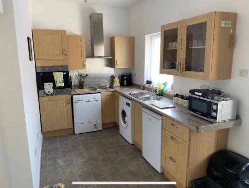 a kitchen with wooden cabinets and a sink and a dishwasher at Lingfield Lodge Ewenique Views pets welcome in Welbury