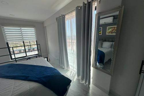 a bedroom with a mirror and a bed and a window at Paulette 901 Loft at Morgan Residences in Cabo San Lucas