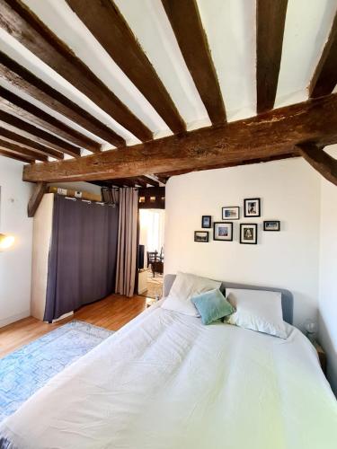 - une chambre avec un grand lit blanc et des poutres en bois dans l'établissement Beau 2 pièces charme et confort, à Dieppe