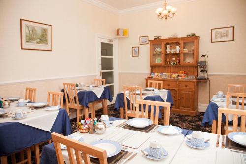 a dining room with tables and chairs and a cabinet at Binton Guest House in Filey