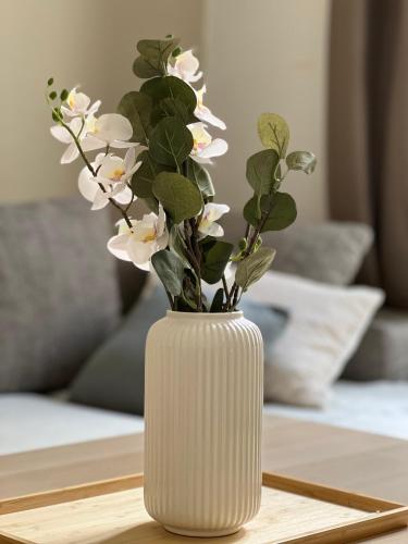 un vase blanc avec des fleurs blanches sur une table dans l'établissement Confort près de Paris 16e Eiffel Tower, JO2024, à Saint-Cloud