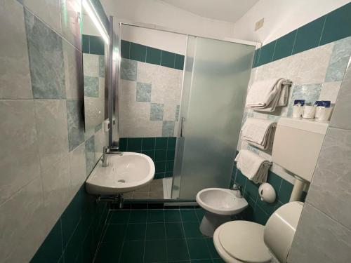 a green and white bathroom with two toilets and a sink at Hotel Cortese in Palermo