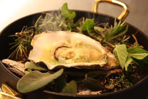 a black bowl of food with an oyster in it at Gargiulo Resort in Sant'Agnello