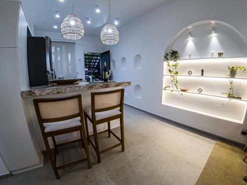 a kitchen with two chairs at a counter with lights at Templo Acqua - Refúgio Sereno na Natureza in Armacao dos Buzios