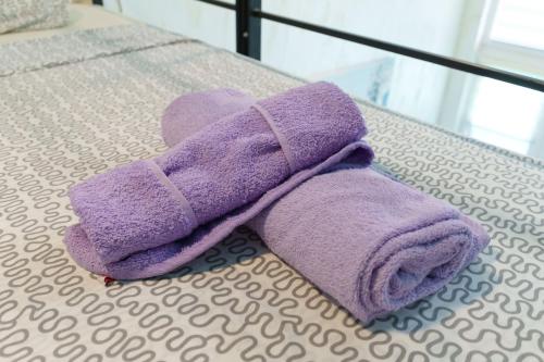 a purple towel is sitting on a bed at Step rooms apt spa in Belgrade