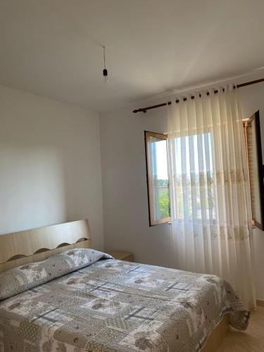 a white bedroom with a bed and a window at Villa Pams in Baks-Rrjoll