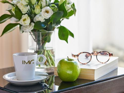 a table with a coffee cup and an apple and glasses at Hotel Rey Alfonso X in Seville