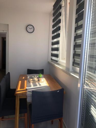 a dining room table with chairs and a clock on the wall at Apartma Šmit in Vir