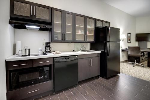 a kitchen with black cabinets and a black refrigerator at Candlewood Suites Waco by IHG in Waco