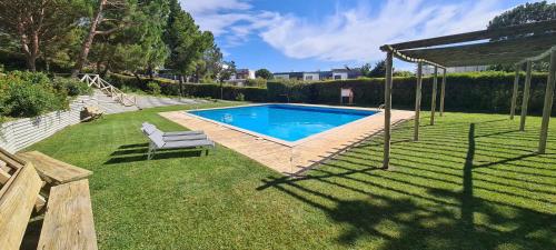 a swimming pool in a yard with a chair at Ananda Troia in Troia