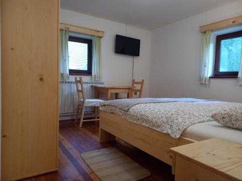 a bedroom with a bed and a desk with a television at The farmhouse Bevsek Osep in Solčava