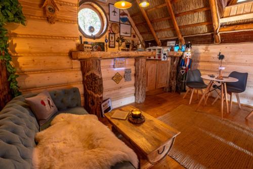 a living room with a couch and a table in a cabin at Pod Kogutem i Sową - Bio Wioska z domkami Premium w góralskim stylu dla dorosłych in Postołowo