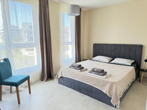 a bedroom with a bed and a chair and windows at Boho and More in Sozopol