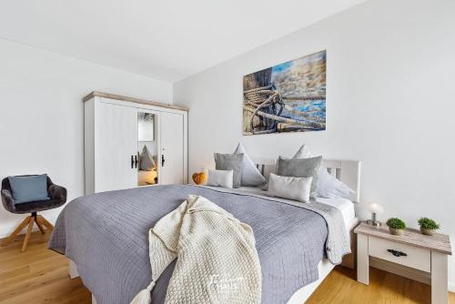 una camera da letto bianca con un letto e una sedia di DEIN Ostseeblick a Kappeln