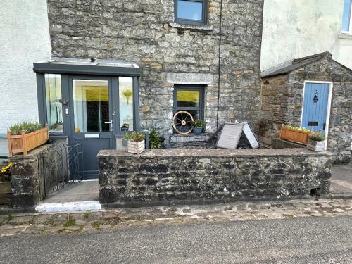 a stone building with a blue door and a window at Pemberton cottage in Ingleton 