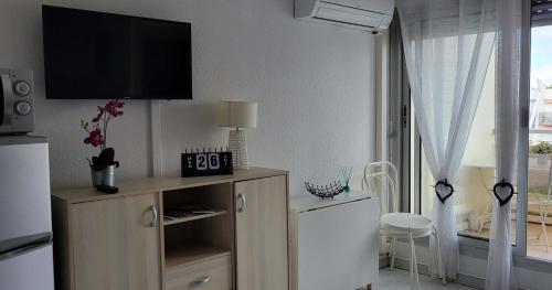 un salon avec une télévision à écran plat au mur dans l'établissement Studio cabine climatisé avec parking au Couchant, à La Grande Motte