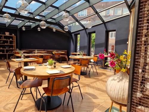 a restaurant with wooden tables and chairs and a brick wall at Chasse Boutique Hotel in Amsterdam