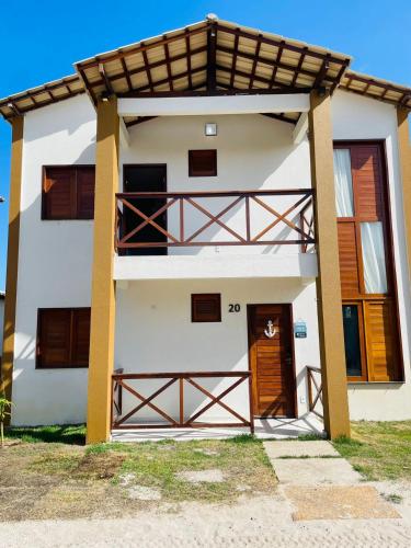 a white house with a gate and a wooden door at Chalé Nautic Atins in Atins