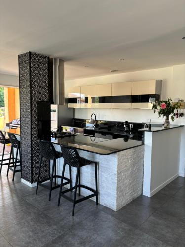 - une cuisine avec un comptoir et quelques chaises dans l'établissement Maison tout confort à proximité des plages, à Villeneuve-Loubet